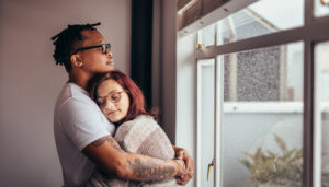 Couple hugging near window thinking about choosing a surrogacy and egg donation agency