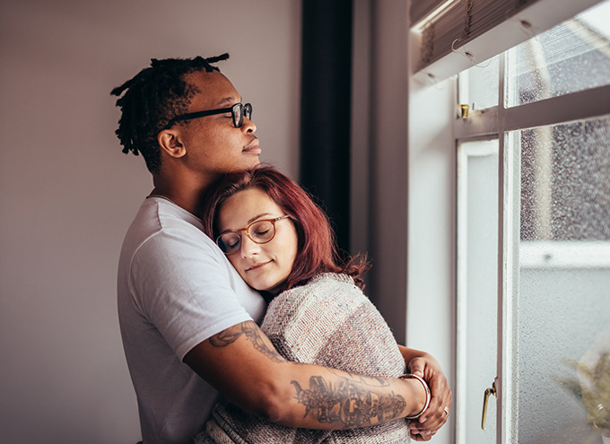 Interracial couple hugging with eyes closed