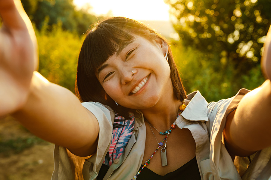 young asian woman smiling at camera while taking a selfie