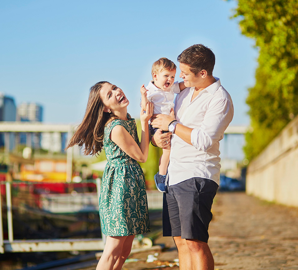 husband and wife laughing with little boy