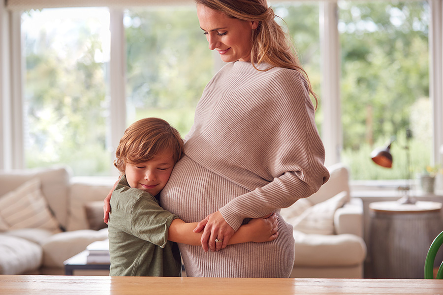 experienced surrogate - son hugging pregnant mother